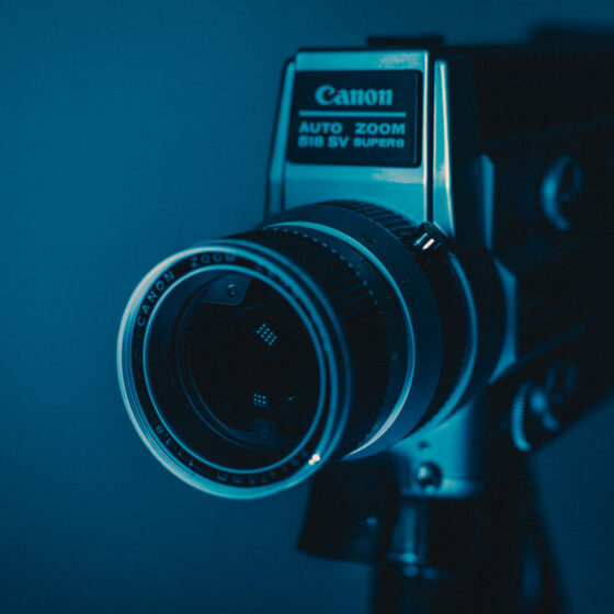 Produkt-Fotografie mit Bildgänger zeigt eine alte Filmkamera, welche im Fotostudio blau beleuchtet wird.